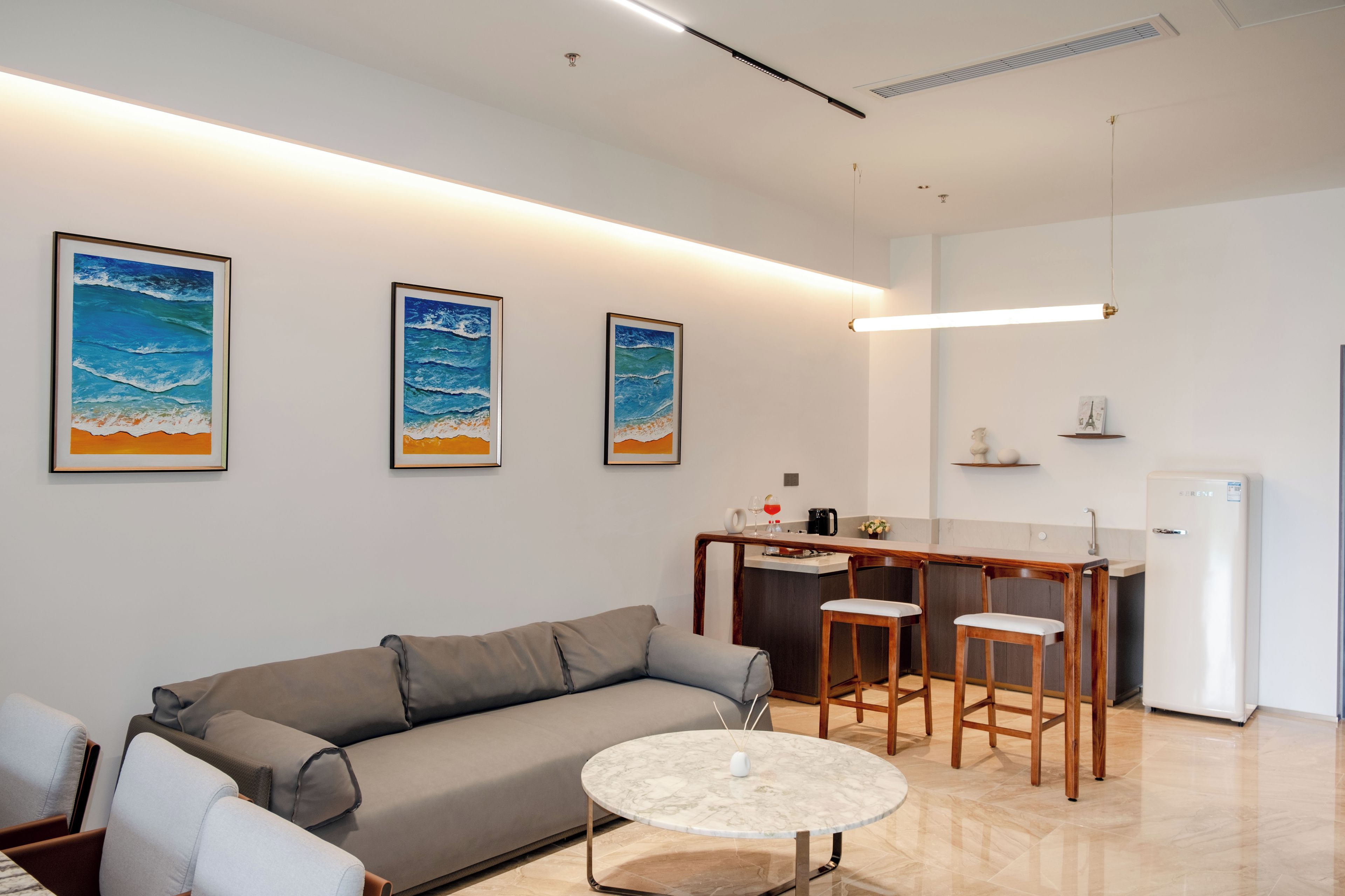 A modern living room with a sofa, a round coffee table, and a kitchen area with a bar.