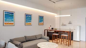 A modern living room with a sofa, a round coffee table, and a kitchen area with a bar.