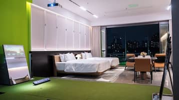 Een moderne hotelkamer met een groot bed, een bureau en een balkon met uitzicht op de stad.