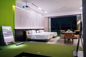 Habitación de hotel moderna con una cama grande, un escritorio y un balcón con vistas a la ciudad.