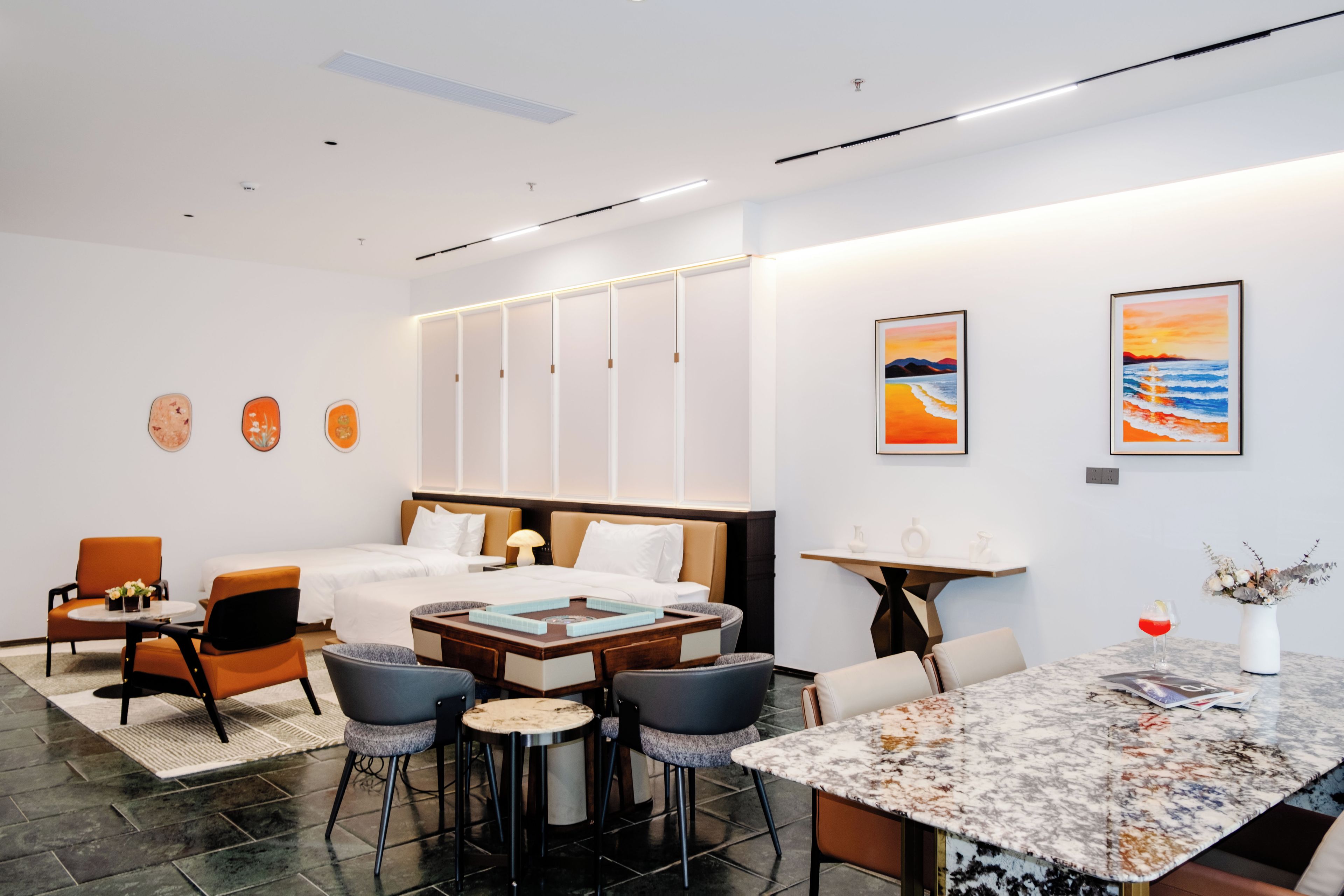 Una habitación de hotel moderna con cama, zona de estar y obras de arte en las paredes.