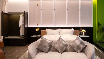 Een hotelkamer met een bed, een slaapbank, een nachtkastje, een lamp en een groene wand.