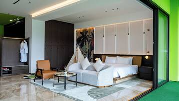 A modern hotel room with a bed, a seating area, and a wardrobe.