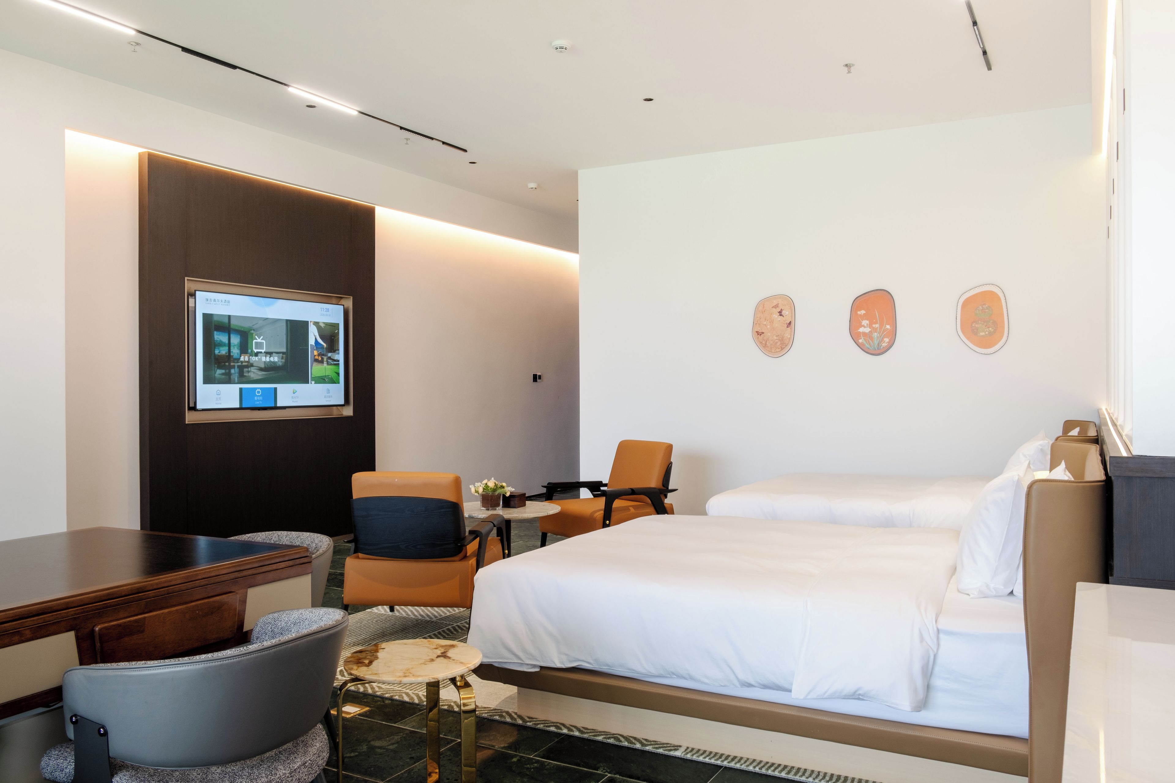 A hotel room with a bed, a desk, a chair, a television, and a wall-mounted artwork.