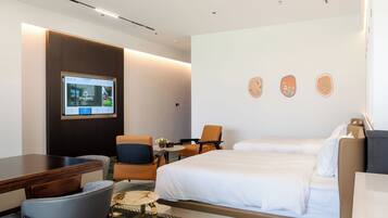 A hotel room with a bed, a desk, a chair, a television, and a wall-mounted artwork.