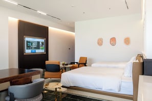 A hotel room with a bed, a desk, a chair, a television, and a wall-mounted artwork. - Sakki Golf Resort (Shenzhen)