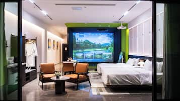 Hotelkamer met een bed, een bureau met stoel, een televisiescherm waarop een golfbaan te zien is, en een badkamer door een geopende deur.