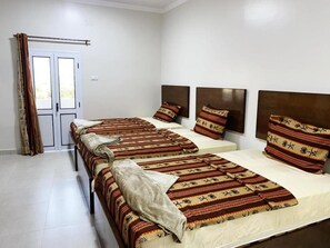 Una habitació d'hotel amb dos llits, una porta amb cortines i vista a l'exterior.