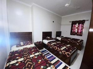 A room with three beds, each with a patterned bedspread and headboard. - Nubian yellow desert (Aswan)