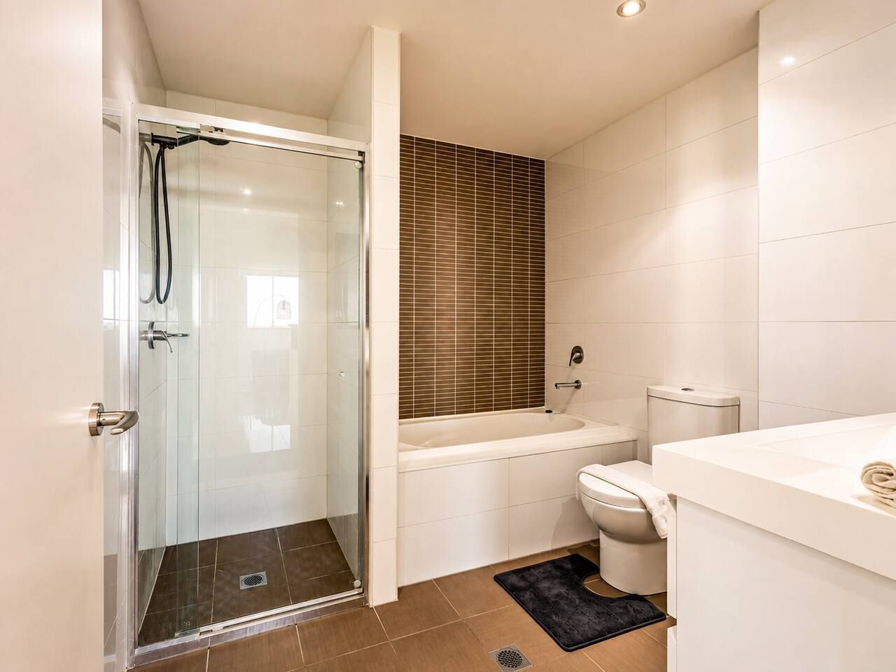 A bathroom with a glass-enclosed shower, a bathtub, a toilet, and a sink.