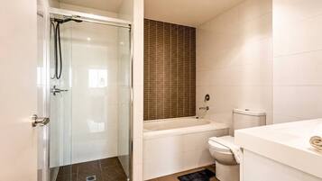 A bathroom with a glass-enclosed shower, a bathtub, a toilet, and a sink.