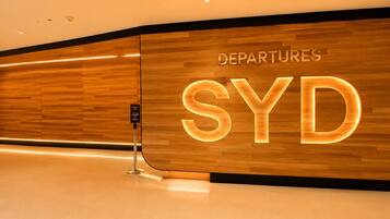 Eine glatte Holzwand mit leuchtendem 'DEPARTURES SYD'-Schild.