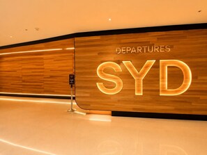 Pareti in legno lucido con insegna illuminata 'DEPARTURES SYD'.