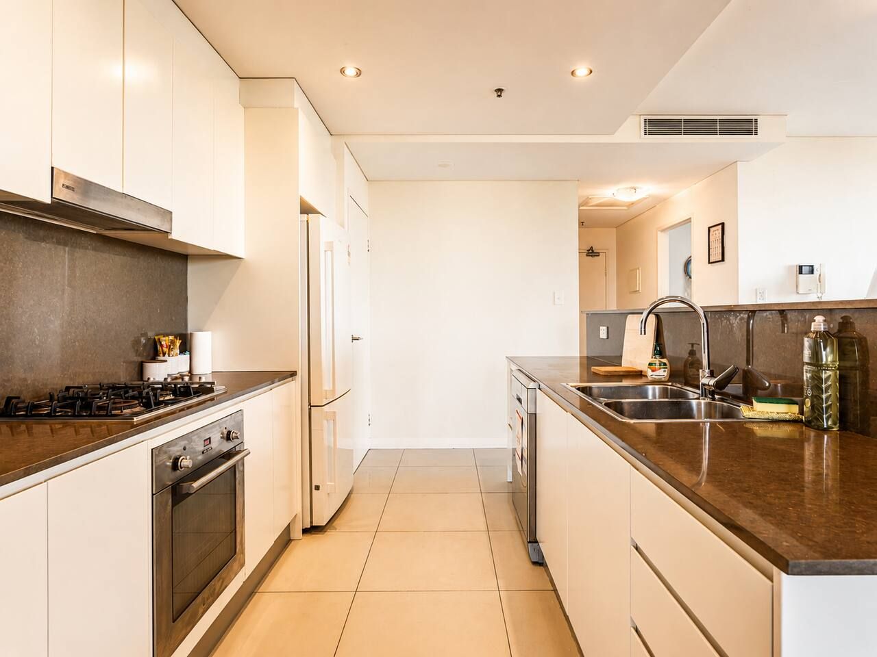 A modern kitchen with white cabinetry, a stainless steel range, and a dark countertop.