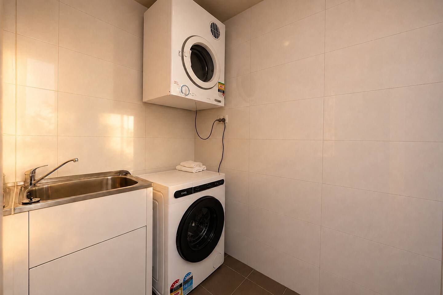 A compact laundry room with a washing machine, a dryer, and a sink.