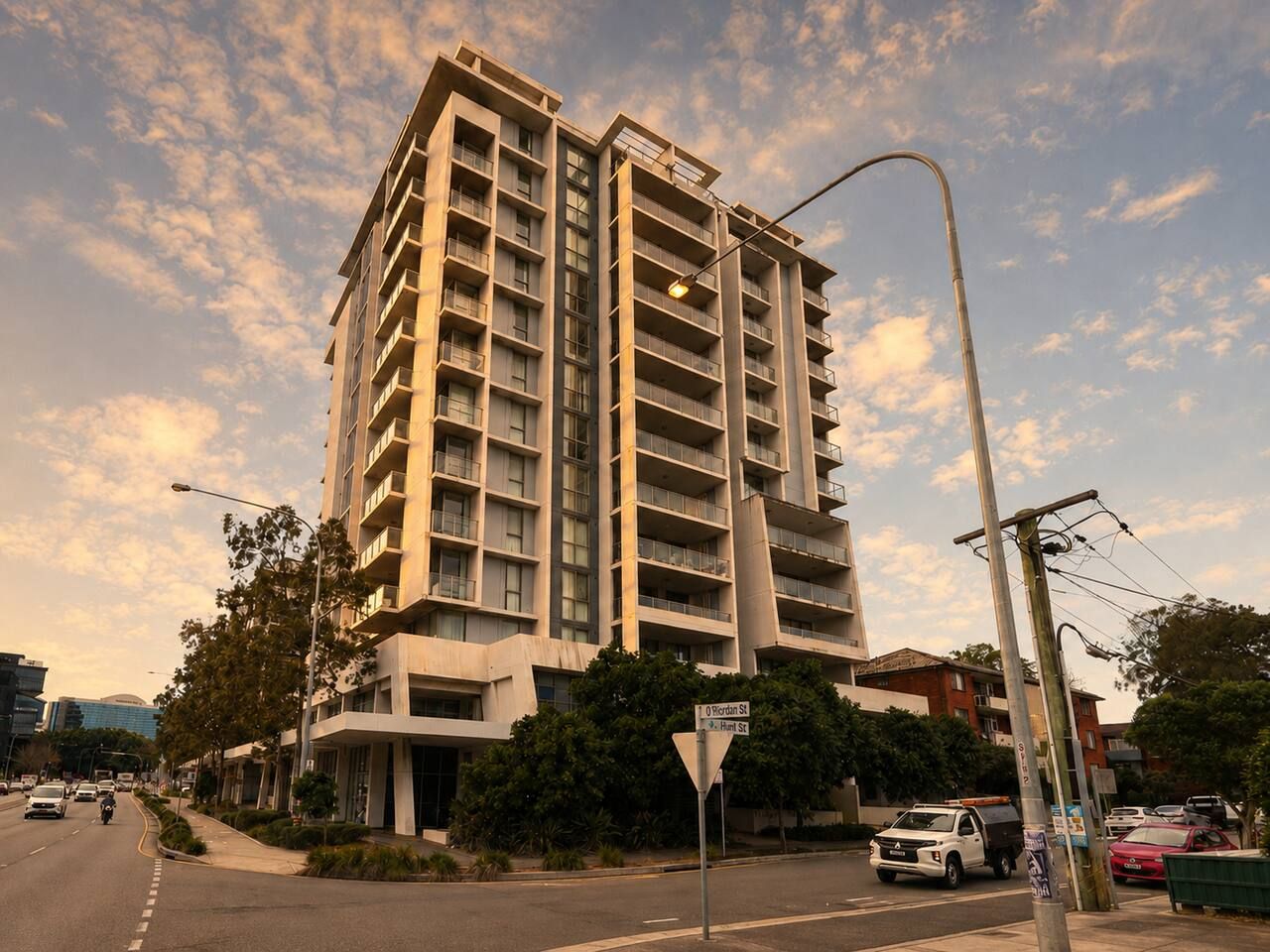 A multi-story building with balconies, located at an intersection with street signs.