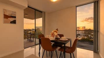 A dining area with a table set for four, large windows offering a city view, and a modern interior design.