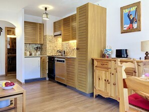 Eine moderne Küche mit Holzschränken, einem eingebauten Backofen und einer Kaffeemaschine.
