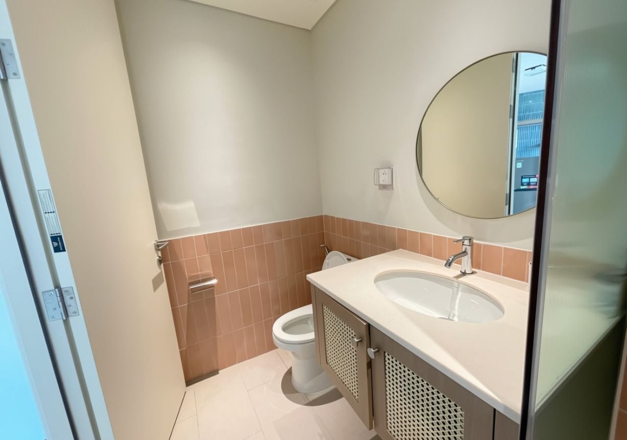 A bathroom with a toilet, sink, and mirror.