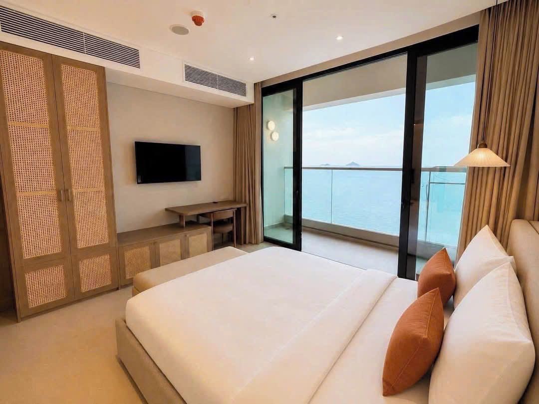Une chambre d’hôtel avec un lit, une télévision, un bureau et un balcon offrant une vue.