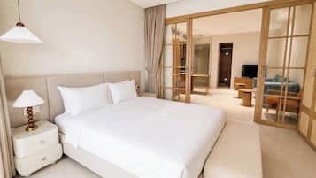 A hotel room with a large bed, a bedside table with a lamp, a sliding glass door leading to a balcony, and a television on a stand.