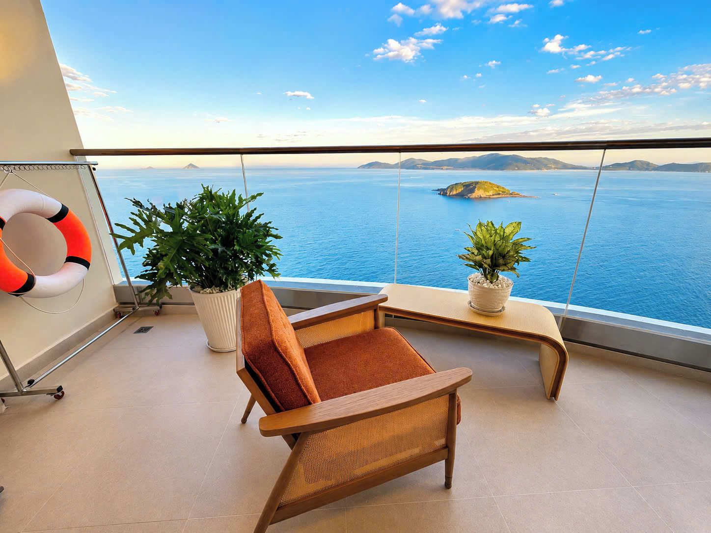 Varanda com vista para o mar, uma cadeira, duas plantas em vasos e um flutuador.