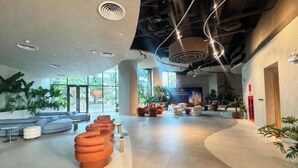 Um hall amplo com área de estar curvo, uma grande janela e design de teto moderno.