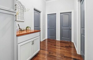 A hallway with wooden flooring, white cabinetry, and two grey doors. - Relax & Play Near Sycuan Casino Resort Sleeps 12 (El Cajon)