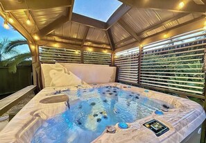 A hot tub with a control panel, surrounded by a covered patio with a view of greenery. - Relax & Play Near Sycuan Casino Resort Sleeps 12 (El Cajon)
