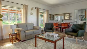 A living room with a sofa, armchairs, a coffee table, and a dining area with a table and chairs.