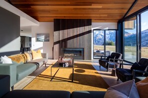 Ein modernes Wohnzimmer mit Kamin, Sitzgelegenheit und Bergblick.