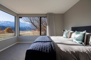 Ein Schlafzimmer mit großem Fenster, einem Bett und einem Nachttisch.