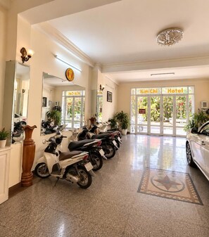 A hotel reception area with a row of parked scooters, a large mirror, and a sign for 'Kim Chi Hotel'. - KIM CHI HOTEL (Da Lat)