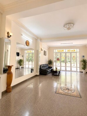 A hotel lobby with a black leather sofa, a wooden vase, and a chandelier. - KIM CHI HOTEL (Da Lat)