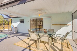 Eine überdachte Terrasse mit einem Glastisch, Stühlen, einem Deckenventilator und Blick ins Freie.