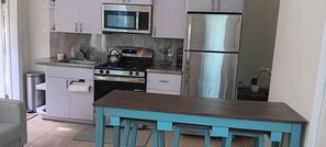 A compact kitchen with a gas stove, microwave, and stainless steel refrigerator. - Executive One-Bedroom Apartment Boasting Natural Light and Lush Scenery! (Charlotte Amalie)