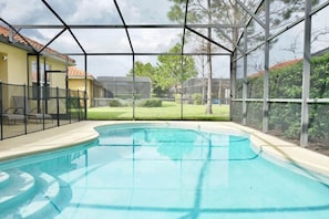 Une piscine dotée d’une zone abritée, entourée d’une clôture et d’arbres.