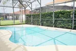 An indoor swimming pool with a clear view of the surrounding area, including a building with a tiled roof and a hedge. - 5 BR Solterra Resort w Private Heated Pool (Davenport)