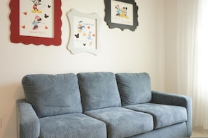 A grey sofa in a room with three framed Disney character pictures on the wall. - 5 BR Solterra Resort w Private Heated Pool (Davenport)