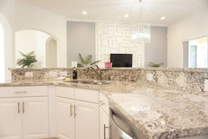 A kitchen with granite countertops, white cabinetry, a built-in oven, and a pendant light. - 5 BR Solterra Resort w Private Heated Pool (Davenport)