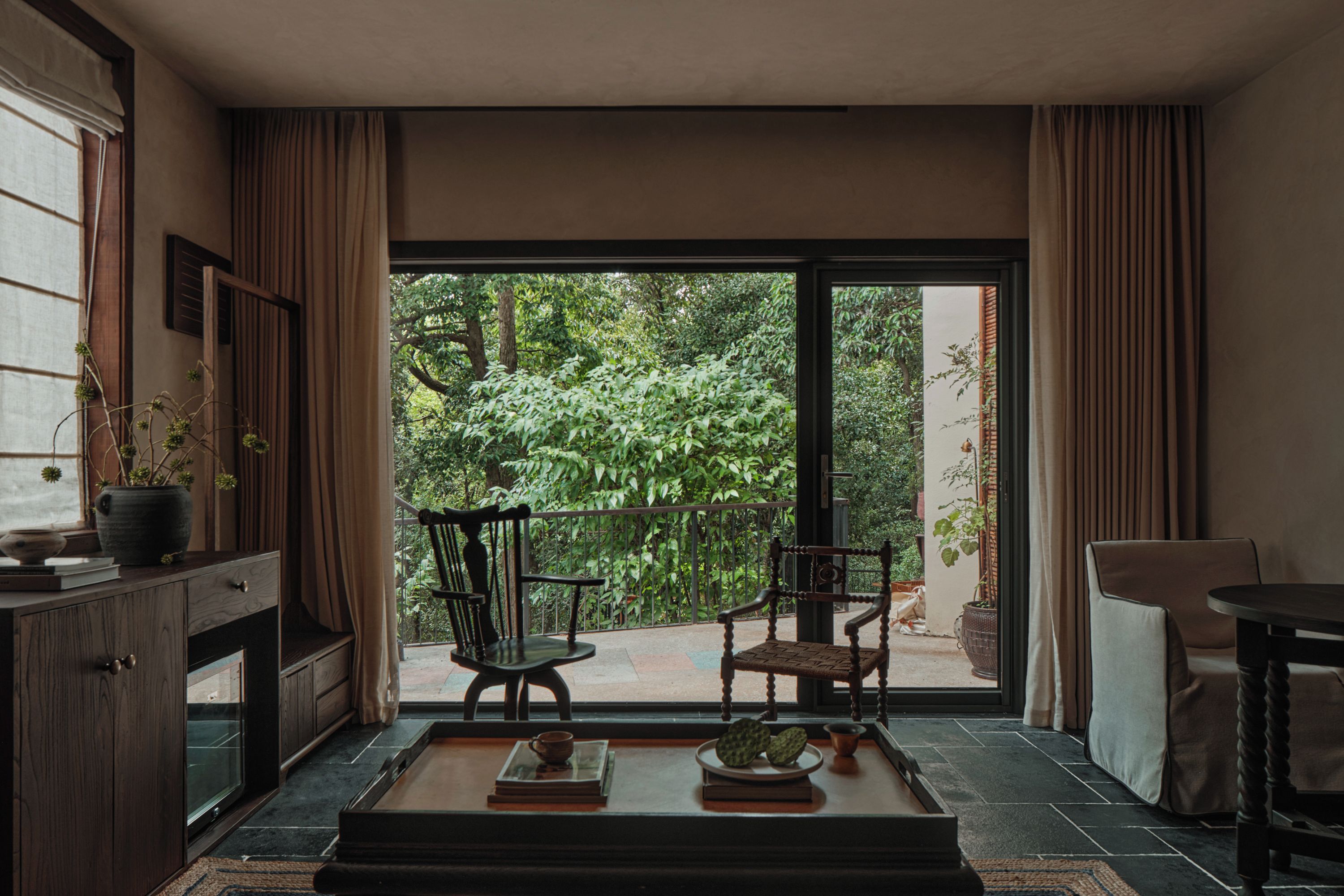A room with a large sliding glass door leading to a balcony with two chairs and a table.