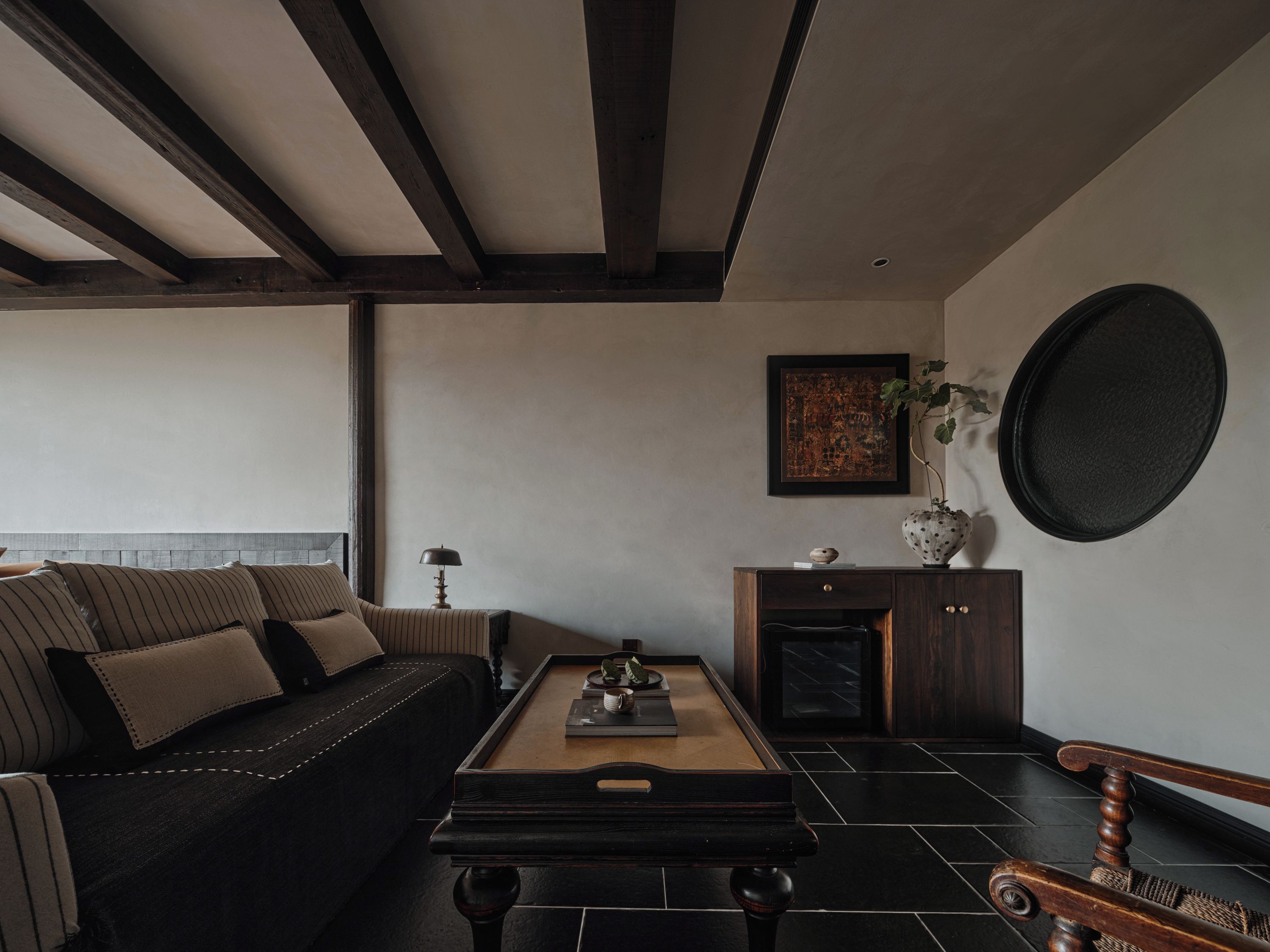 A modern living room with a dark sofa, a wooden coffee table, and a dark wooden cabinet.