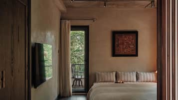 A bedroom with a large bed, a flat-screen TV, a framed artwork, and a view through a window.