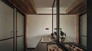 A modern bathroom with a wooden ceiling, a large mirror, and a tray with toiletries.