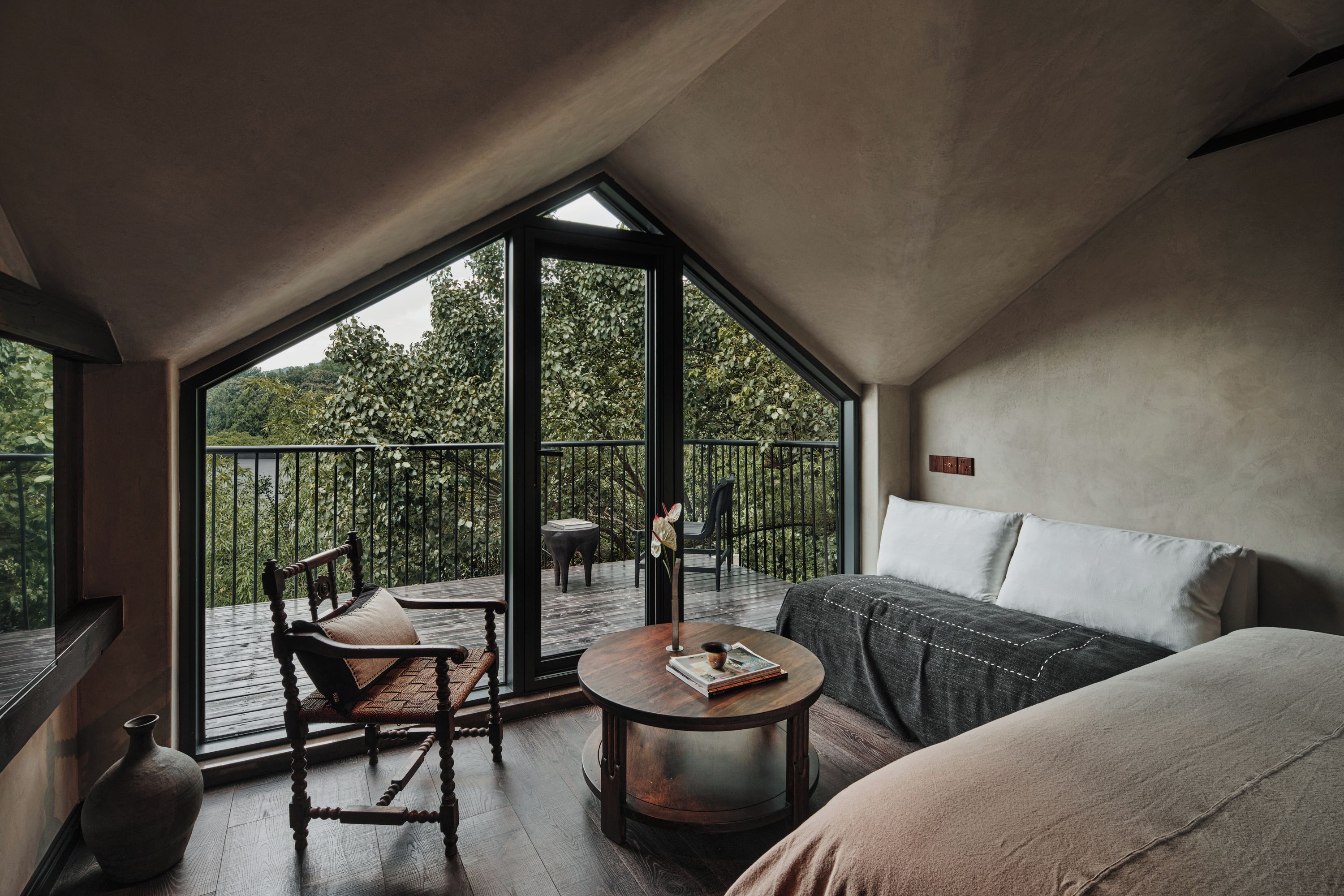 A room with a large window, a sofa, a round table, and a chair.
