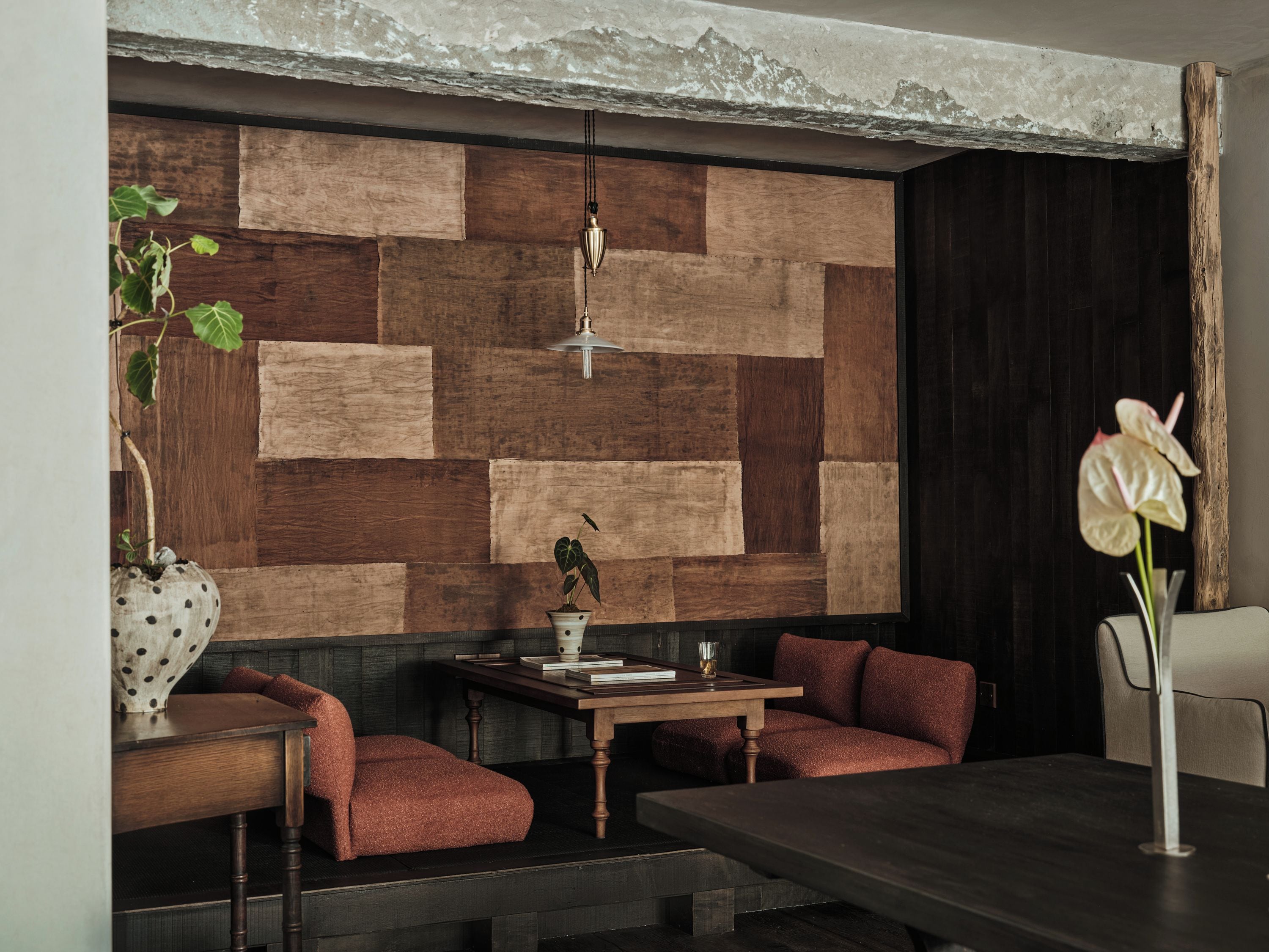 Een modern interieur met een houten wandpaneel, een eettafel, zitplaatsen en een hanglamp.
