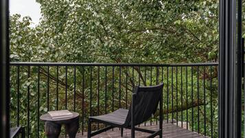 A wooden deck with a metal railing, a black chair, and a small round table.