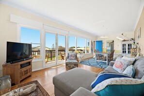Ein geräumiges Wohnzimmer mit Fernseher, einer Sitzecke und Blick ins Freie.