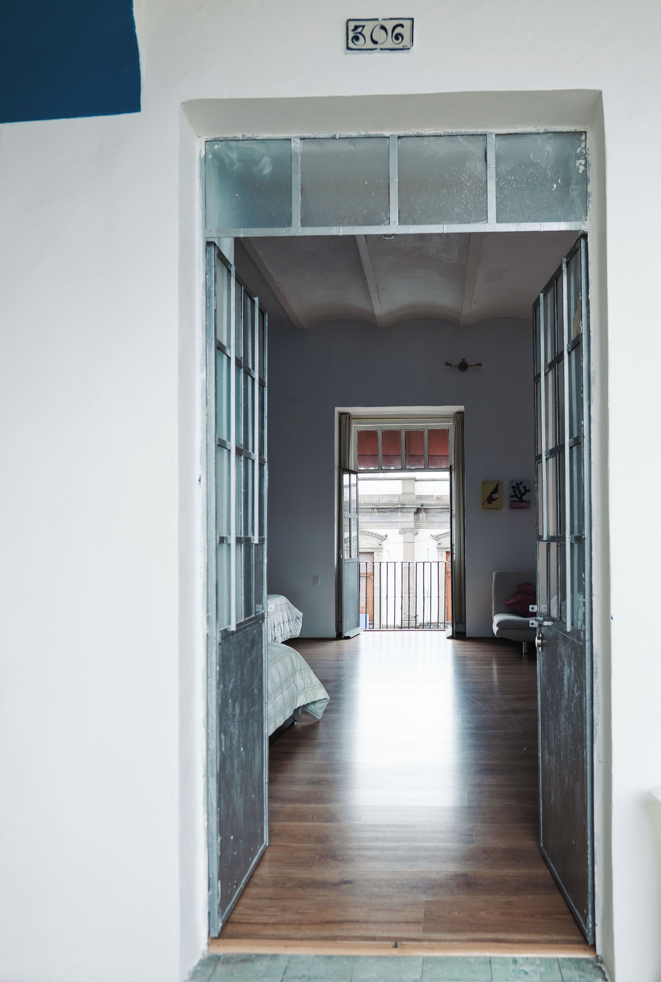 A hallway with a bed, a door, and a view of an outdoor area.