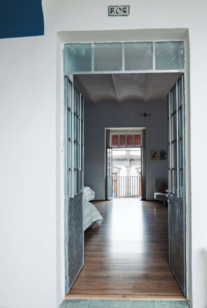 Un pasillo con una cama, una puerta y vistas a un espacio exterior.
